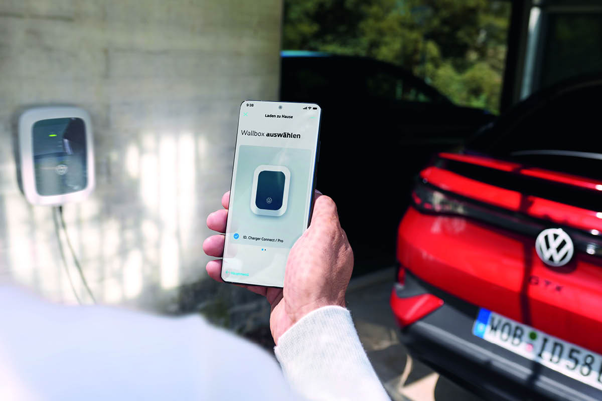 zu sehen ist ein Handy mit Text: Wallbox auswählen, im Hintergrund ist ein roter VW